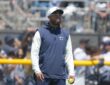 Cowboys defensive coordinator Christian Parker watches a drill at training camp holding a tennis ball.