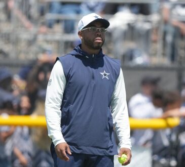 Cowboys defensive coordinator Christian Parker watches a drill at training camp holding a tennis ball.