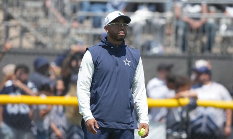 Cowboys defensive coordinator Christian Parker watches a drill at training camp holding a tennis ball.