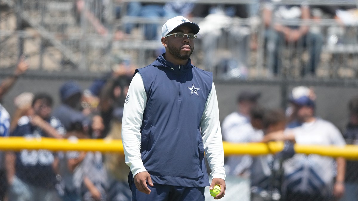 Cowboys defensive coordinator Christian Parker watches a drill at training camp holding a tennis ball.