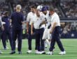 Dallas Cowboys cornerback Cobie Durant walks off the field with team staff on either side of him.