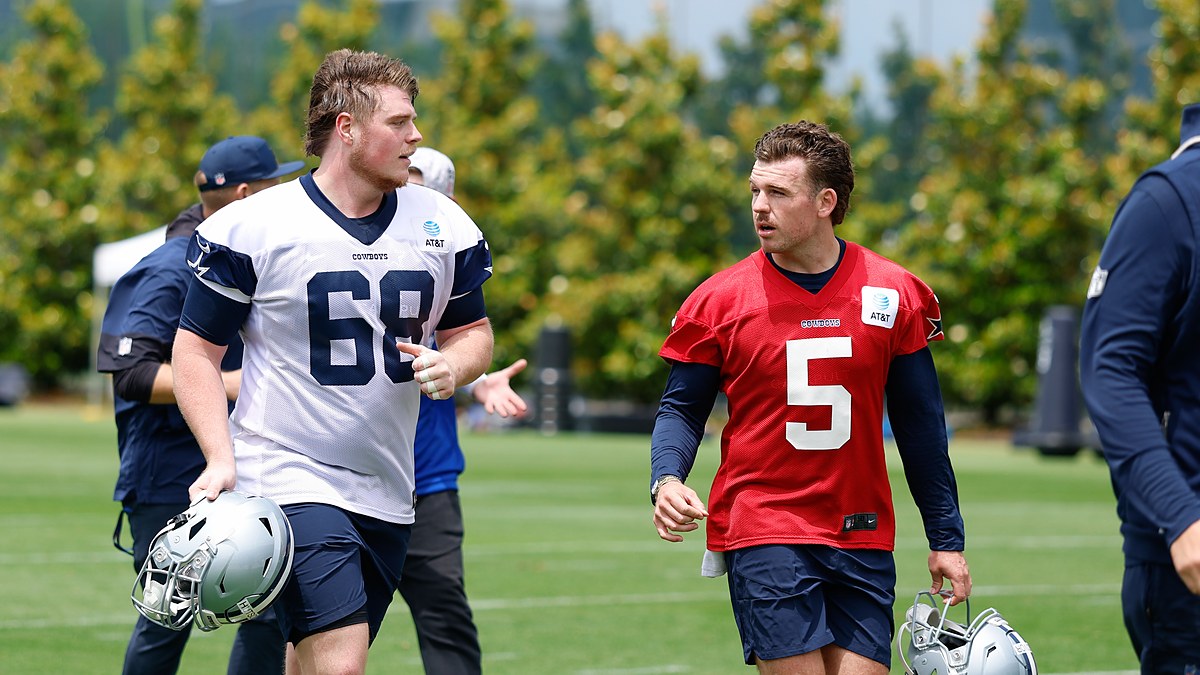 as Cowboys offensive tackle Cole Hutson and quarterback Maverick McIvor jog off the field carrying their helmets.