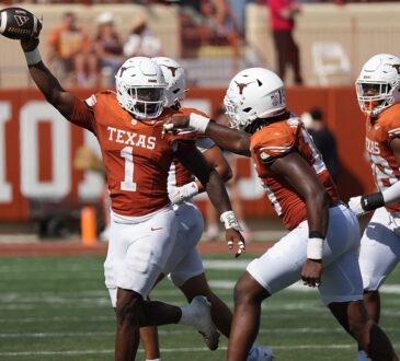 Texas Longhorns edge rusher Colin Simmons, No. 1, holds the ball overhead after recovering a fumble.