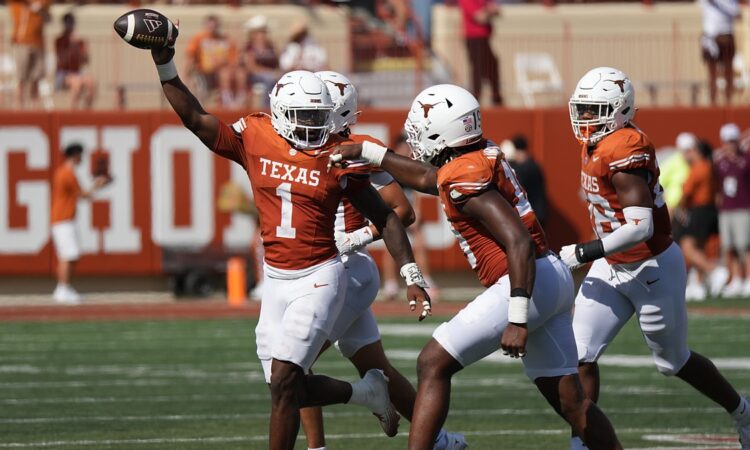 Texas Longhorns edge rusher Colin Simmons, No. 1, holds the ball overhead after recovering a fumble.