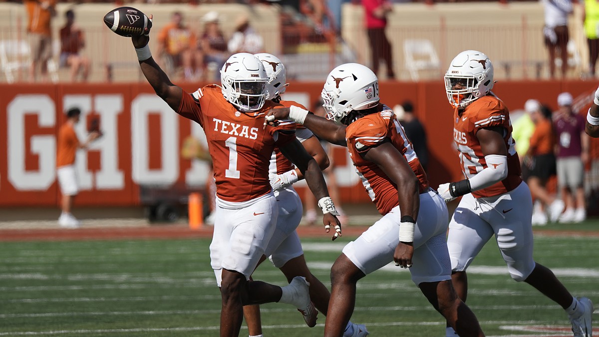 Texas Longhorns edge rusher Colin Simmons, No. 1, holds the ball overhead after recovering a fumble.