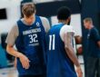 Dallas Mavericks forward Cooper Flagg and guard Kyrie Irving walk side by side in blue practice jerseys during a team practice.