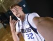 Dallas Mavericks forward Cooper Flagg flashes a hand sign while holding the camera out for a wide-angle selfie.