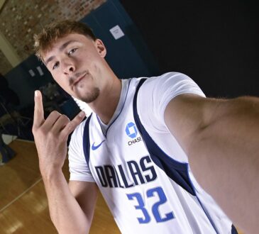 Dallas Mavericks forward Cooper Flagg flashes a hand sign while holding the camera out for a wide-angle selfie.