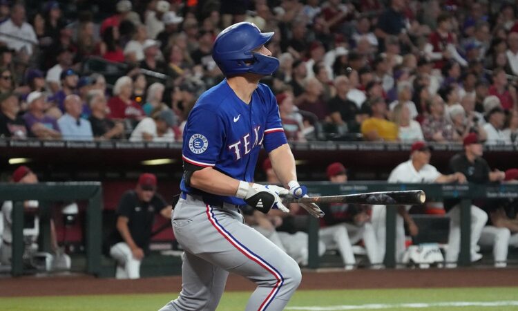 Texas Rangers shortstop Corey Seager follows through on a swing and watches the ball leave the park.