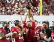 Indiana Hoosiers head coach Curt Cignetti raises the College Football Playoff trophy as players celebrate around him.