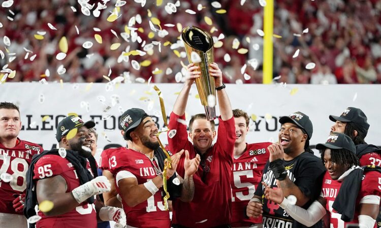 Indiana Hoosiers head coach Curt Cignetti raises the College Football Playoff trophy as players celebrate around him.