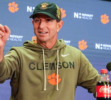 Clemson head coach Dabo Swinney raises an index finger while speaking at a postgame news conference.
