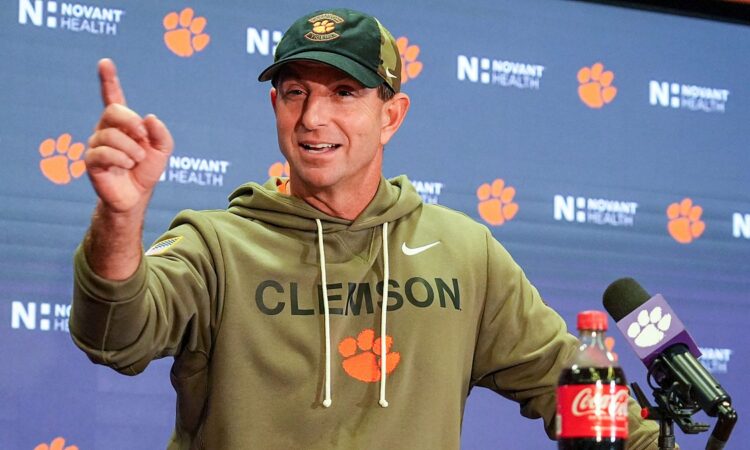 Clemson head coach Dabo Swinney raises an index finger while speaking at a postgame news conference.