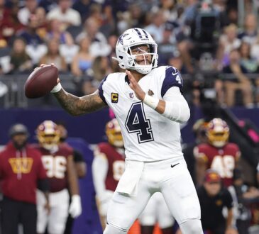 Dallas Cowboys quarterback Dak Prescott cocks his arm to throw from the pocket with the Commanders sideline behind him.