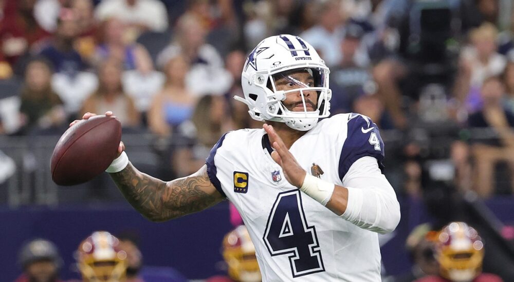 Dallas Cowboys quarterback Dak Prescott cocks the ball back to throw in his white road-style jersey.