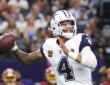 Dallas Cowboys quarterback Dak Prescott cocks the ball back to throw in his white road-style jersey.