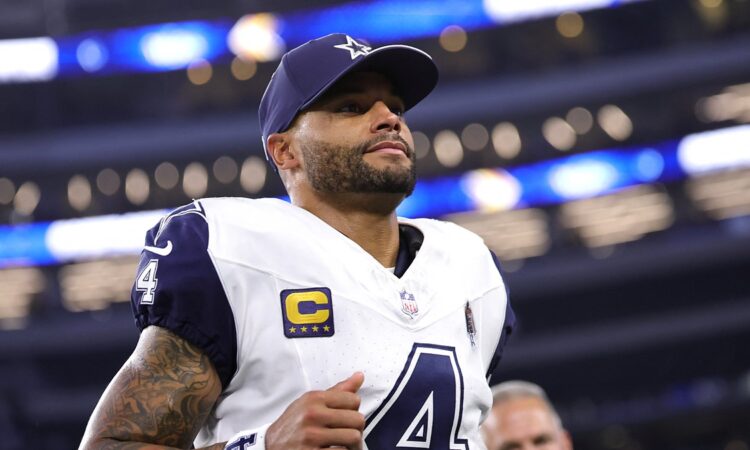 Cowboys quarterback Dak Prescott, wearing a navy cap and his captain’s patch, jogs off the field inside the stadium.