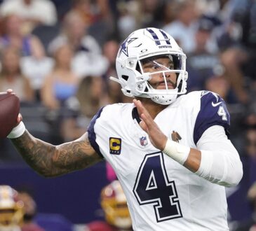 Dallas Cowboys quarterback Dak Prescott cocks the ball back to throw in his white road-style jersey.