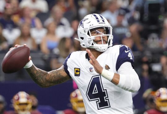 Dallas Cowboys quarterback Dak Prescott cocks the ball back to throw in his white road-style jersey.