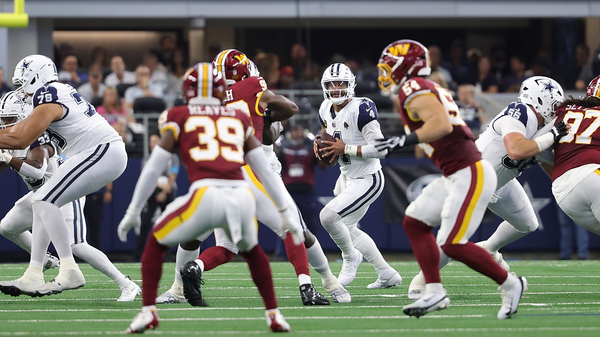 Cowboys quarterback Dak Prescott sets up in the pocket with the football as linemen battle around him.
