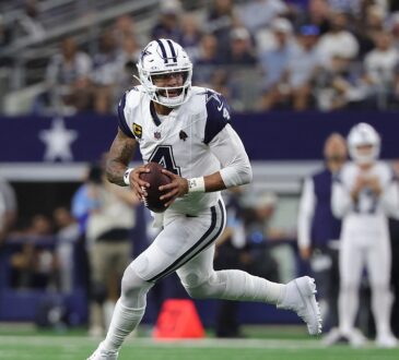 Cowboys quarterback Dak Prescott scrambles to his right with the football in both hands as he looks downfield.