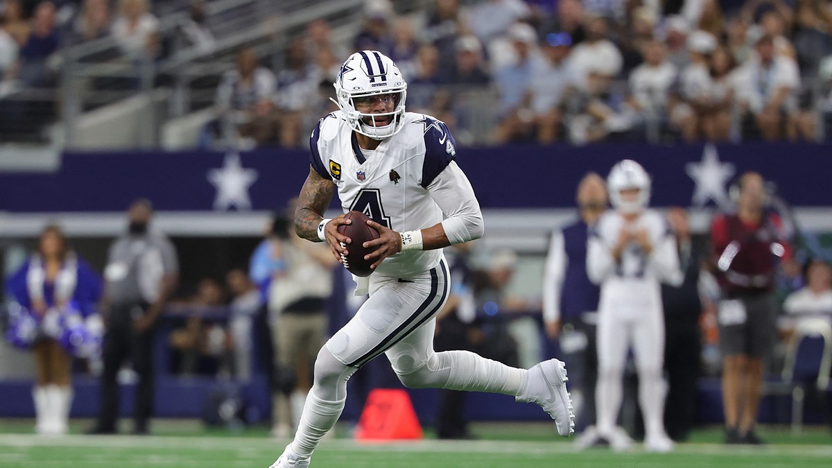 Cowboys quarterback Dak Prescott scrambles to his right with the football in both hands as he looks downfield.