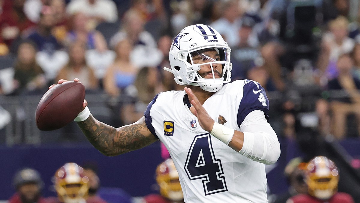 Dallas Cowboys quarterback Dak Prescott cocks the ball back to throw in his white road-style jersey.