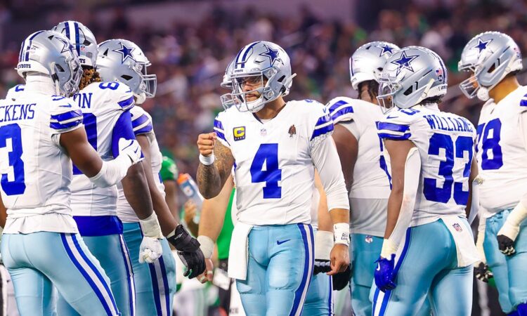Dallas Cowboys quarterback Dak Prescott raises a fist toward wide receiver George Pickens in the huddle against the Eagles.