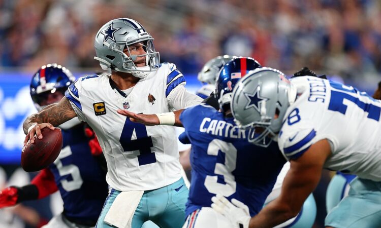 Dallas Cowboys quarterback Dak Prescott winds up to throw as blockers and a Giants rusher fill the pocket.