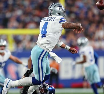 Dallas Cowboys quarterback Dak Prescott releases a pass as a New York Giants defender tackles him low.