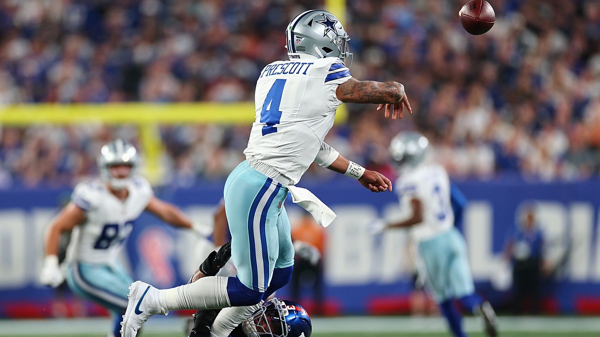 Dallas Cowboys quarterback Dak Prescott releases a pass as a New York Giants defender tackles him low.