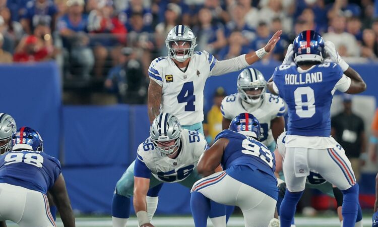 Cowboys quarterback Dak Prescott points out a defender at the line of scrimmage with center Cooper Beebe over the ball.