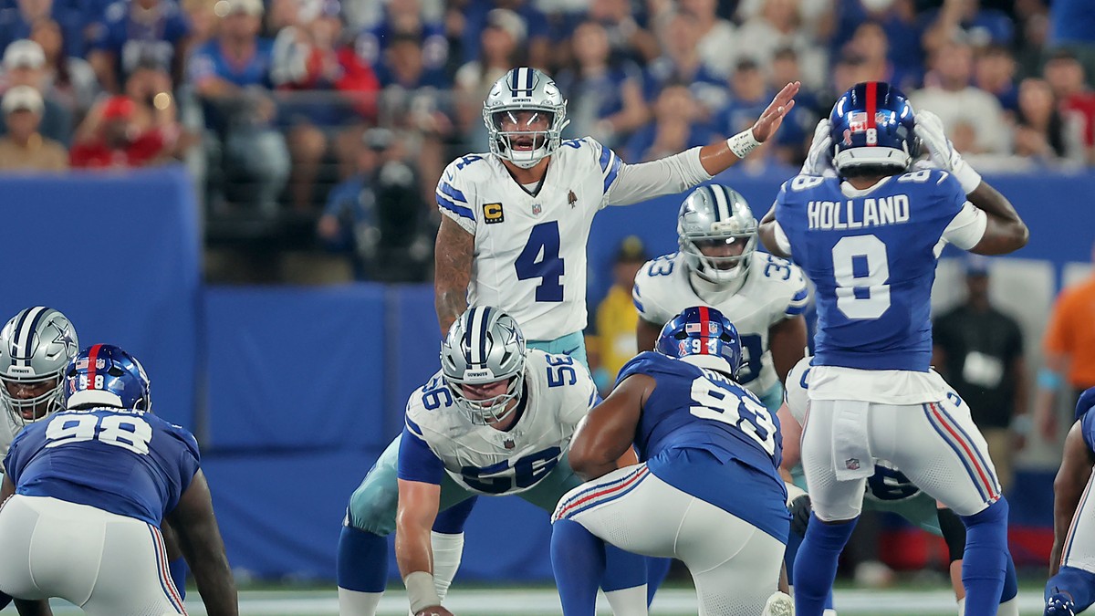 Cowboys quarterback Dak Prescott points out a defender at the line of scrimmage with center Cooper Beebe over the ball.