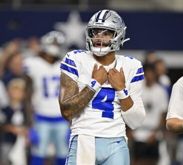 Dallas Cowboys quarterback Dak Prescott adjusts his jersey as he looks on before a game against the Saints.