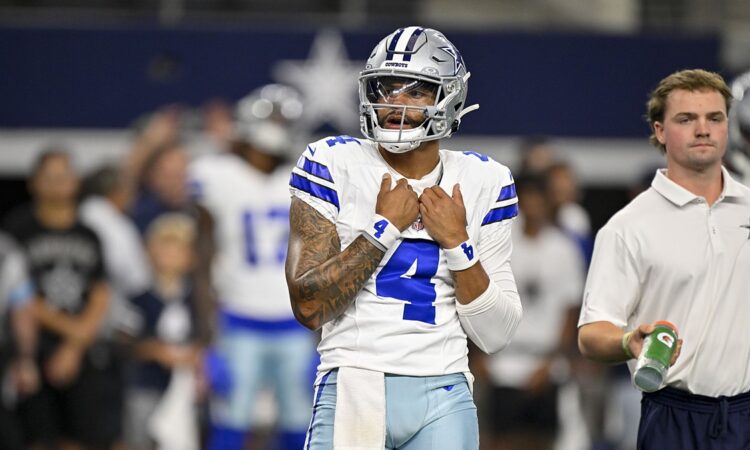 Dallas Cowboys quarterback Dak Prescott adjusts his jersey as he looks on before a game against the Saints.