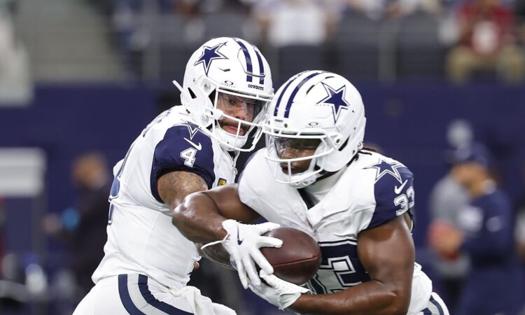 Dallas Cowboys quarterback Dak Prescott hands the ball to running back Javonte Williams during pregame warmups.