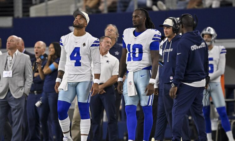 Dallas Cowboys quarterbacks Dak Prescott and Joe Milton III watch from the sideline at AT&T Stadium.