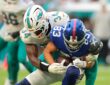 New York Giants wide receiver Dalen Cambre is wrapped up by a Miami Dolphins defender while carrying the ball.