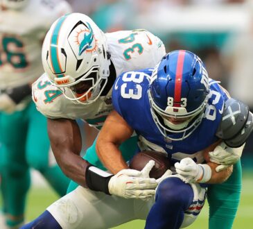 New York Giants wide receiver Dalen Cambre is wrapped up by a Miami Dolphins defender while carrying the ball.