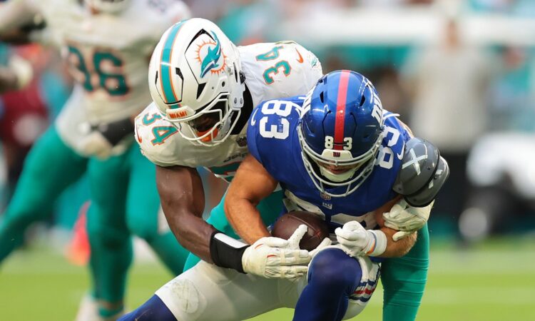 New York Giants wide receiver Dalen Cambre is wrapped up by a Miami Dolphins defender while carrying the ball.