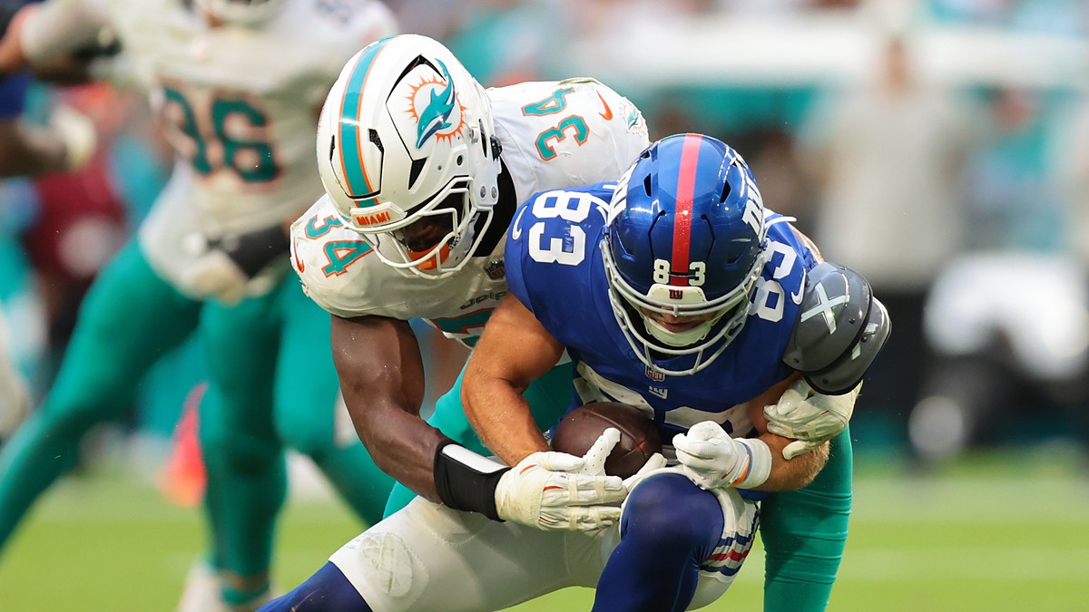 New York Giants wide receiver Dalen Cambre is wrapped up by a Miami Dolphins defender while carrying the ball.