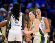 Dallas Wings players huddle on the court in white home uniforms before a game.