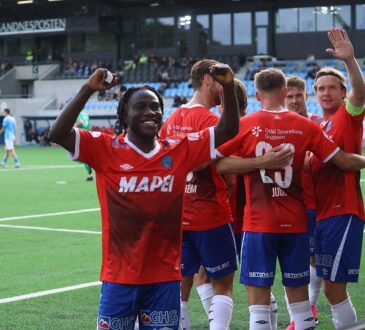 KIL Toppfotball players in red celebrate in front of the away supporters after a goal.