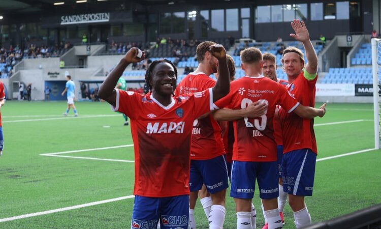 KIL Toppfotball players in red celebrate in front of the away supporters after a goal.