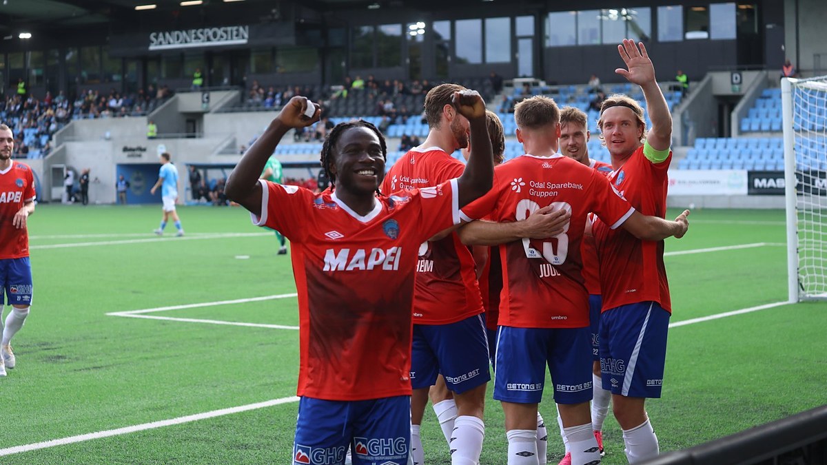 KIL Toppfotball players in red celebrate in front of the away supporters after a goal.