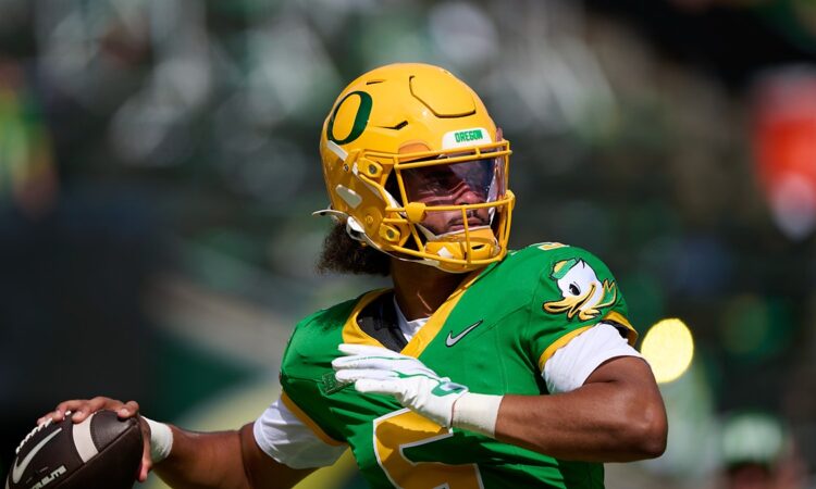 Oregon Ducks quarterback Dante Moore, No. 5, cocks his arm to throw during pregame warmups.