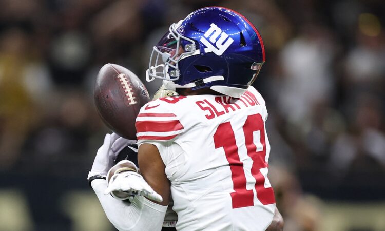 New York Giants wide receiver Darius Slayton reaches for a pass as a Saints cornerback covers him from behind.