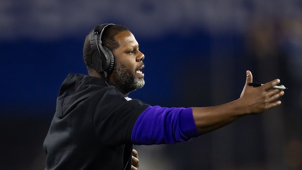 Coach Daronte Jones extends an arm and calls out instructions from the sideline in a headset.