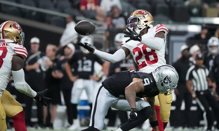 San Francisco 49ers cornerback Darrell Luter Jr. reaches back to break up a pass as the ball floats free.