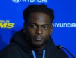 Los Angeles Rams wide receiver Davante Adams sits at a microphone in front of a Rams backdrop, glancing to the side.
